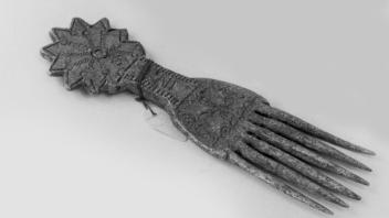 West African aluminum comb with star-shaped rosette handle.